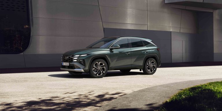 The Hyundai TUCSON Plug in Hybrid parked next to a modern building.